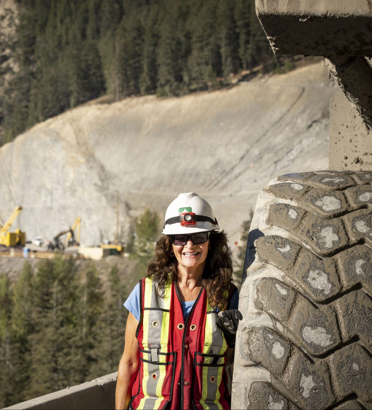 A picture of British Columbia Infrastructure Benefits employee named Dawn standing beside a tire