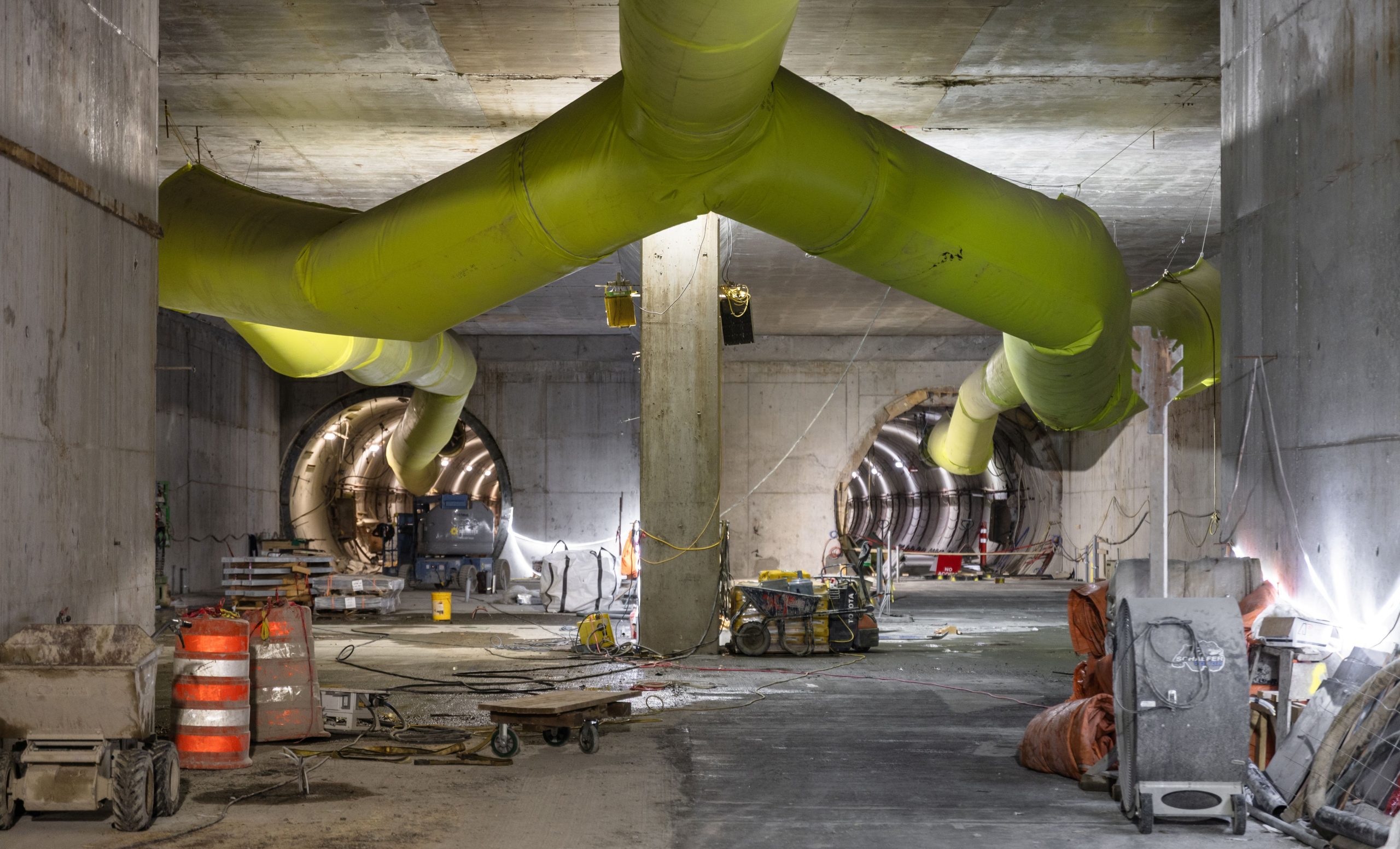 Two tunnels on a subway train construction site, with lights all around.