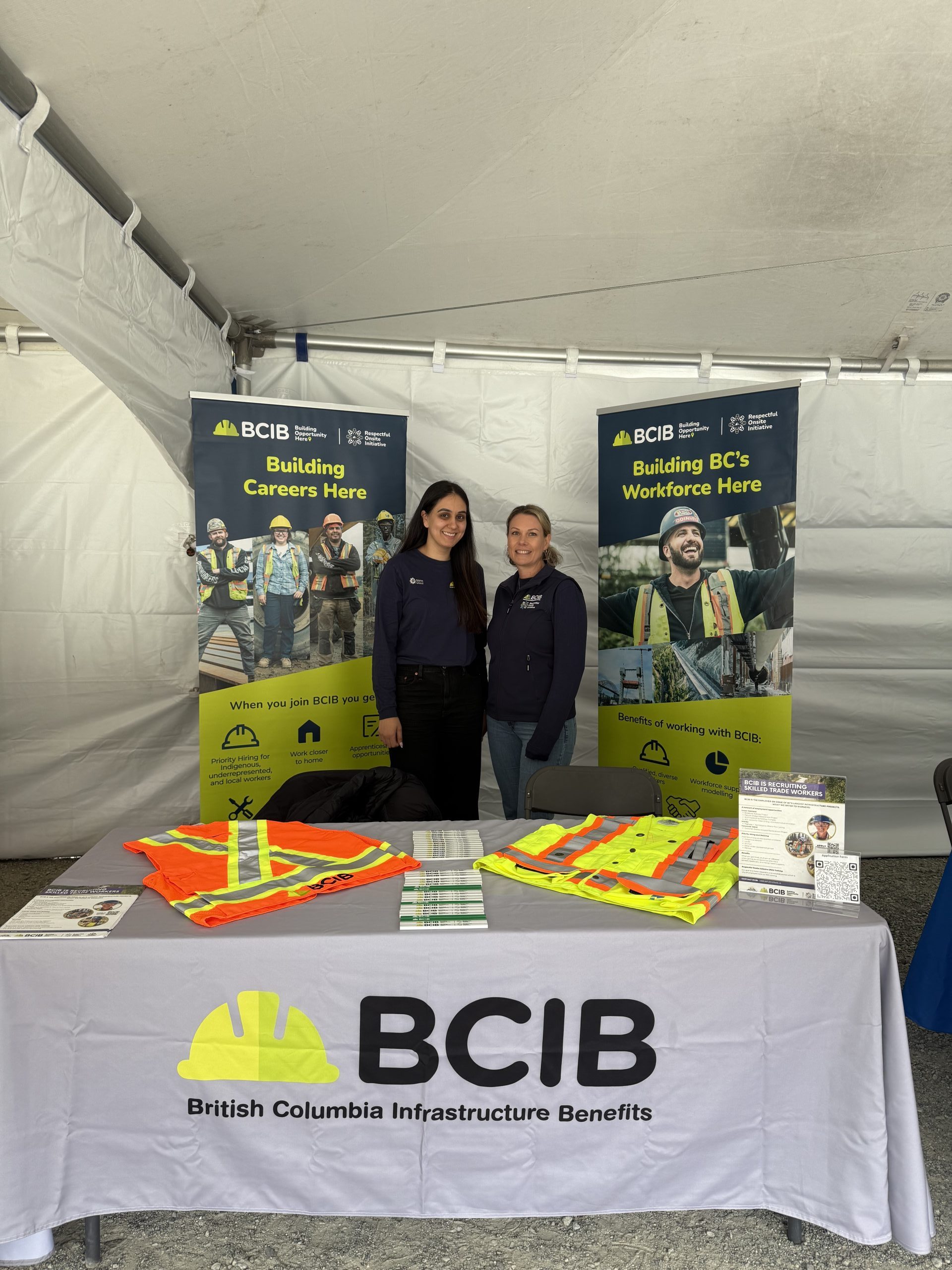 Two women posing for a phot with construction phots in the background.