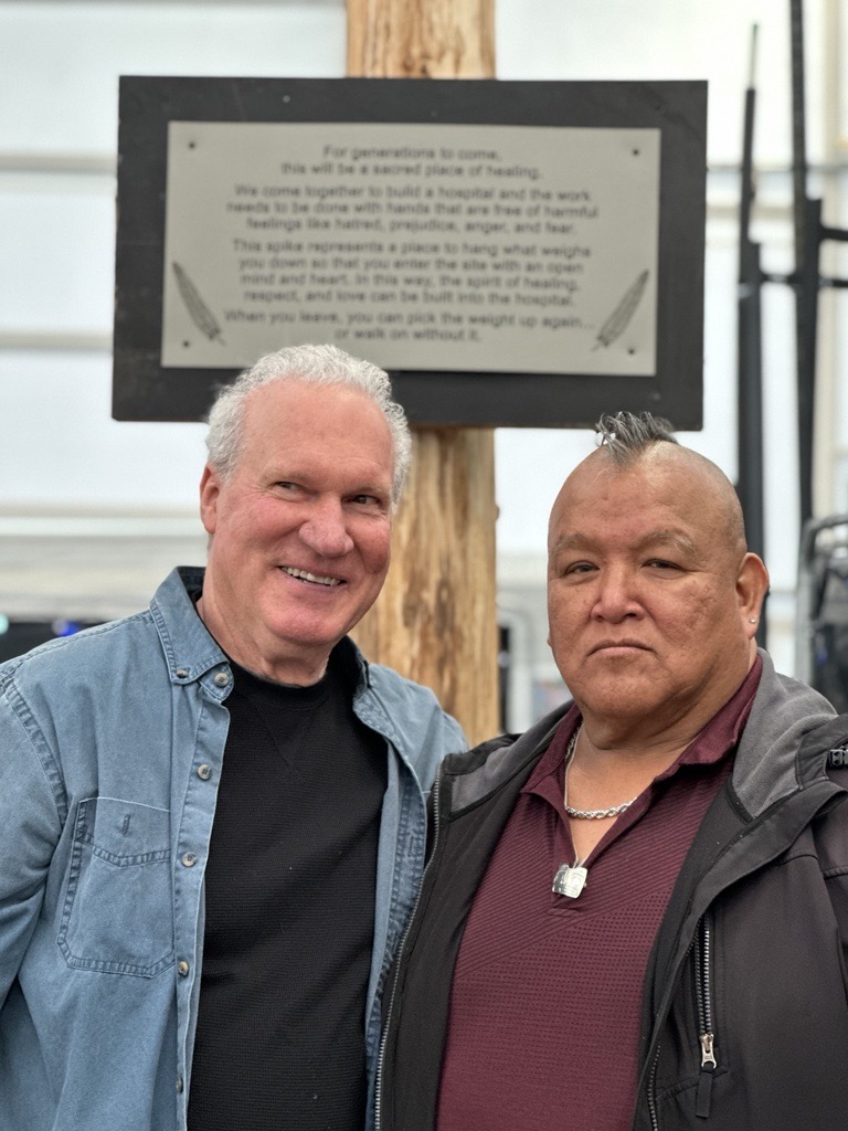 Bubba and Richard smiling in front of the post and plaque.