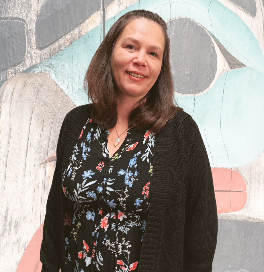 Misty Williams of WorkBC Duncan smiles at camera with a large image of a totem pole in the background.